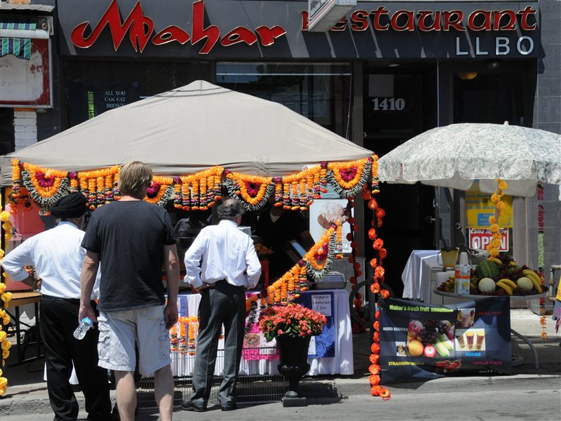 people lining up at booths on the street decorated with flowers at Festival of South Asia