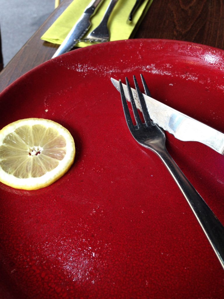 empty red crepe plate with a slice of lemon