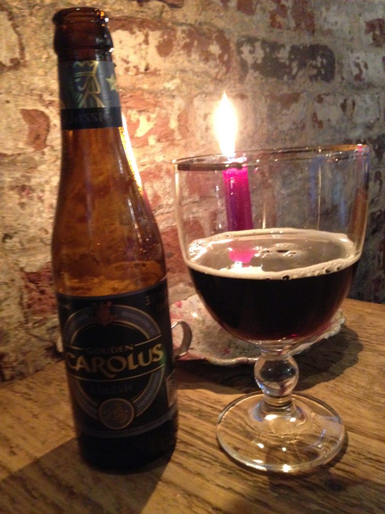 Gouden Carolus Classic Belgian Beer in a glass and bottle, with a candle on the table