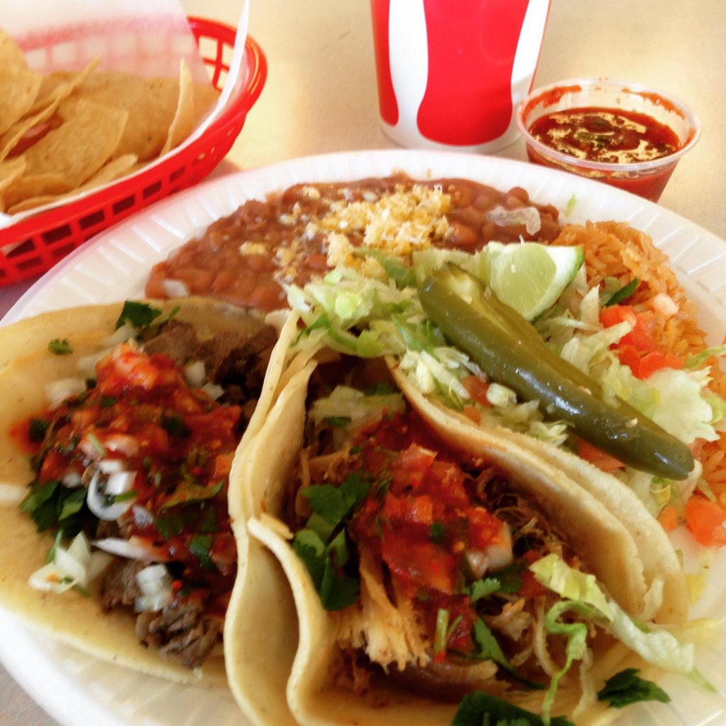 Taco plate with beans and rice, tortilla chips and a soft drink