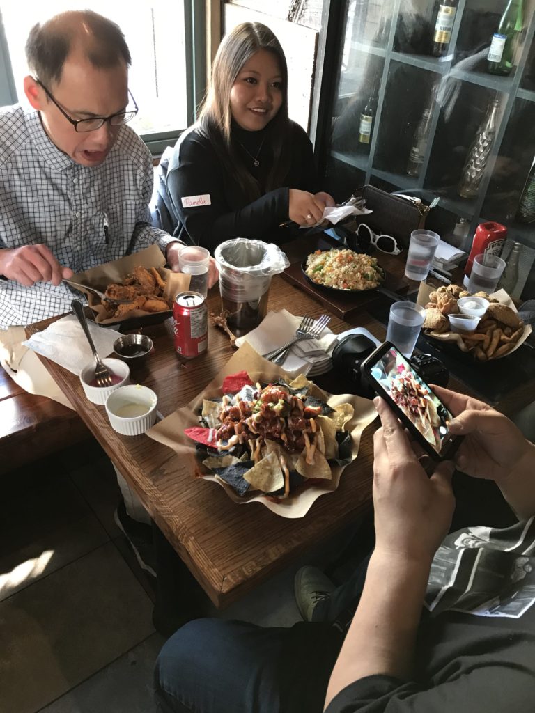 Korean Fried Chicken dishes fill a table with four people eating