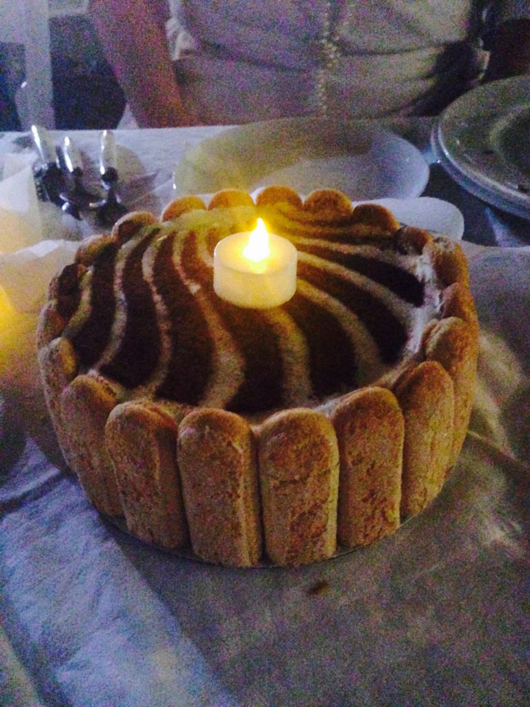 A tiramisu cake with battery operated candle on top
