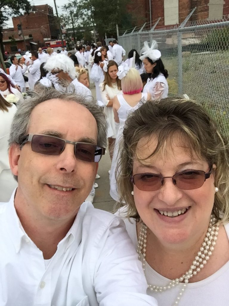 Couple dressed in white surrounded by others also in white garb.