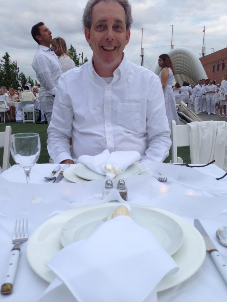 Man sitting at table with place settings in white