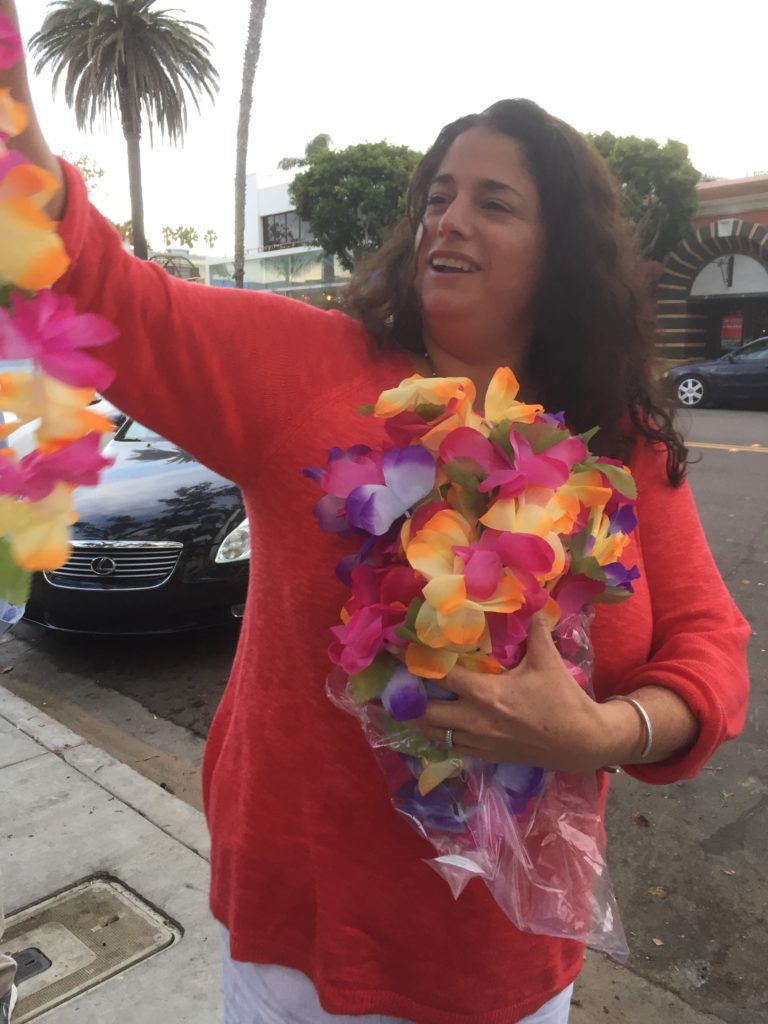 woman holds many Hawaiian style leis