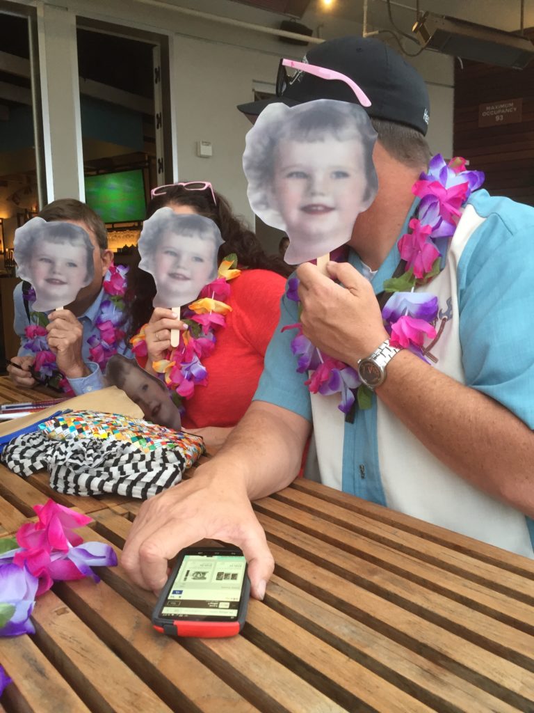 three people hold up face cut-outs in front of their faces