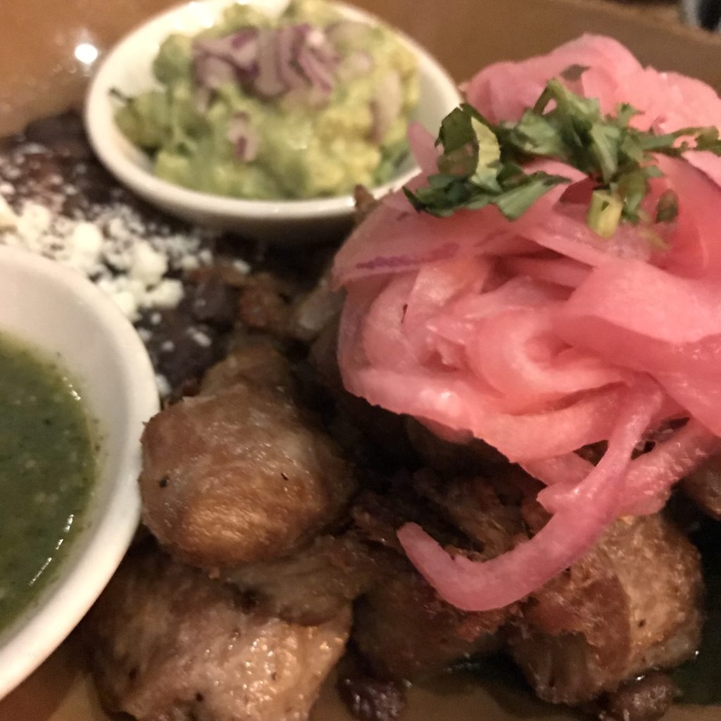 carnitas plate with pickled onions, refried beans and guacamole