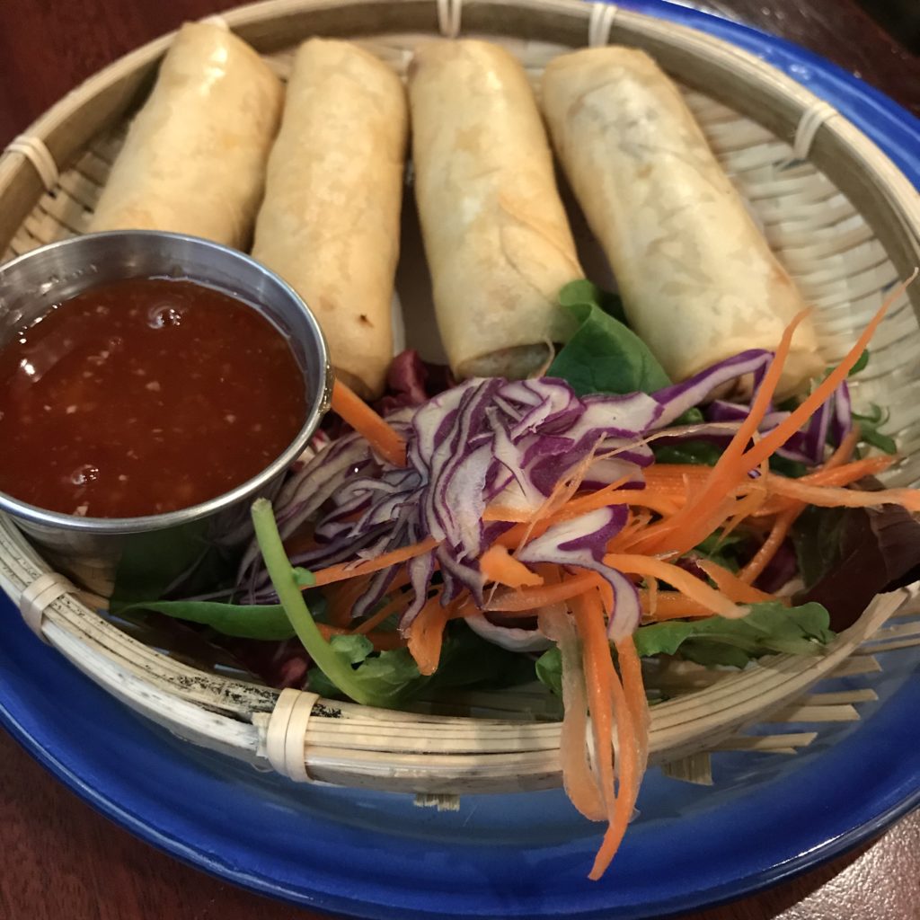 spring rolls on a plate with sauce and decorative vegetables at Moo Pa Thai in Long Beach