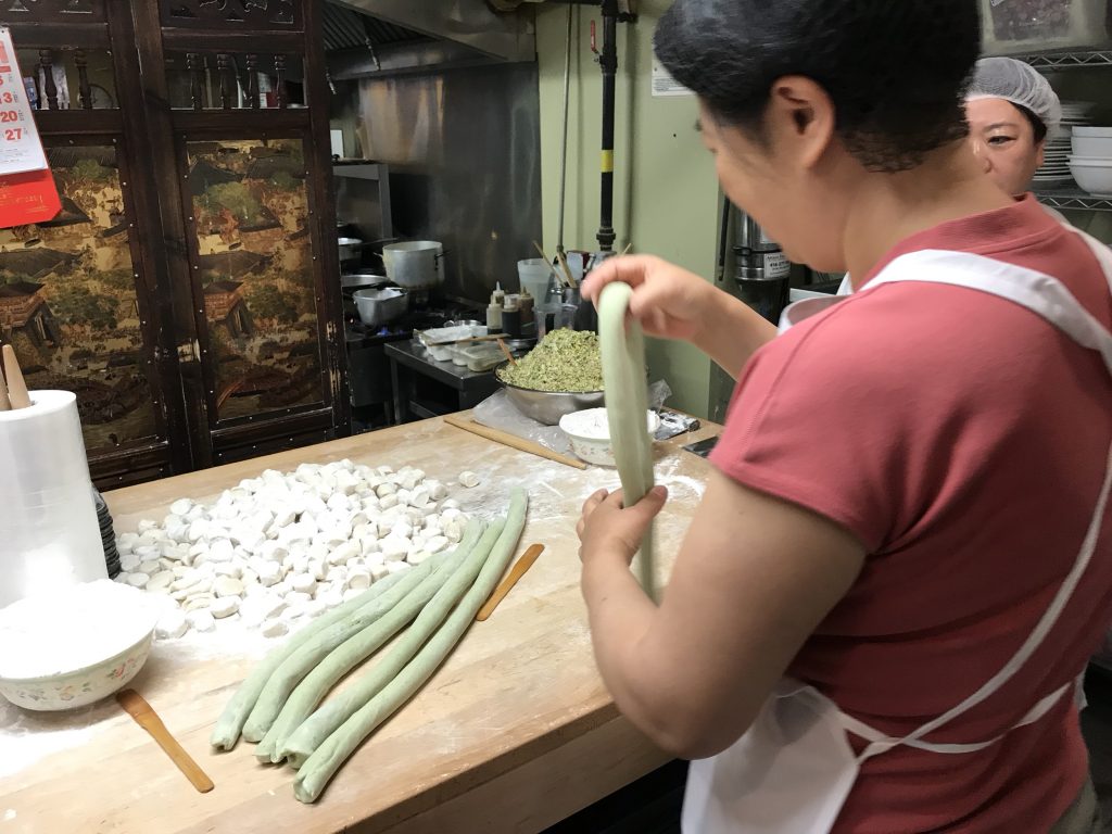 woman forming long rolls of dough for dumplings